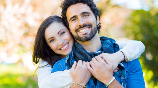 Newcastle Specialist Prosthodontics Two women smiling and laughing while hugging each other outdoors.